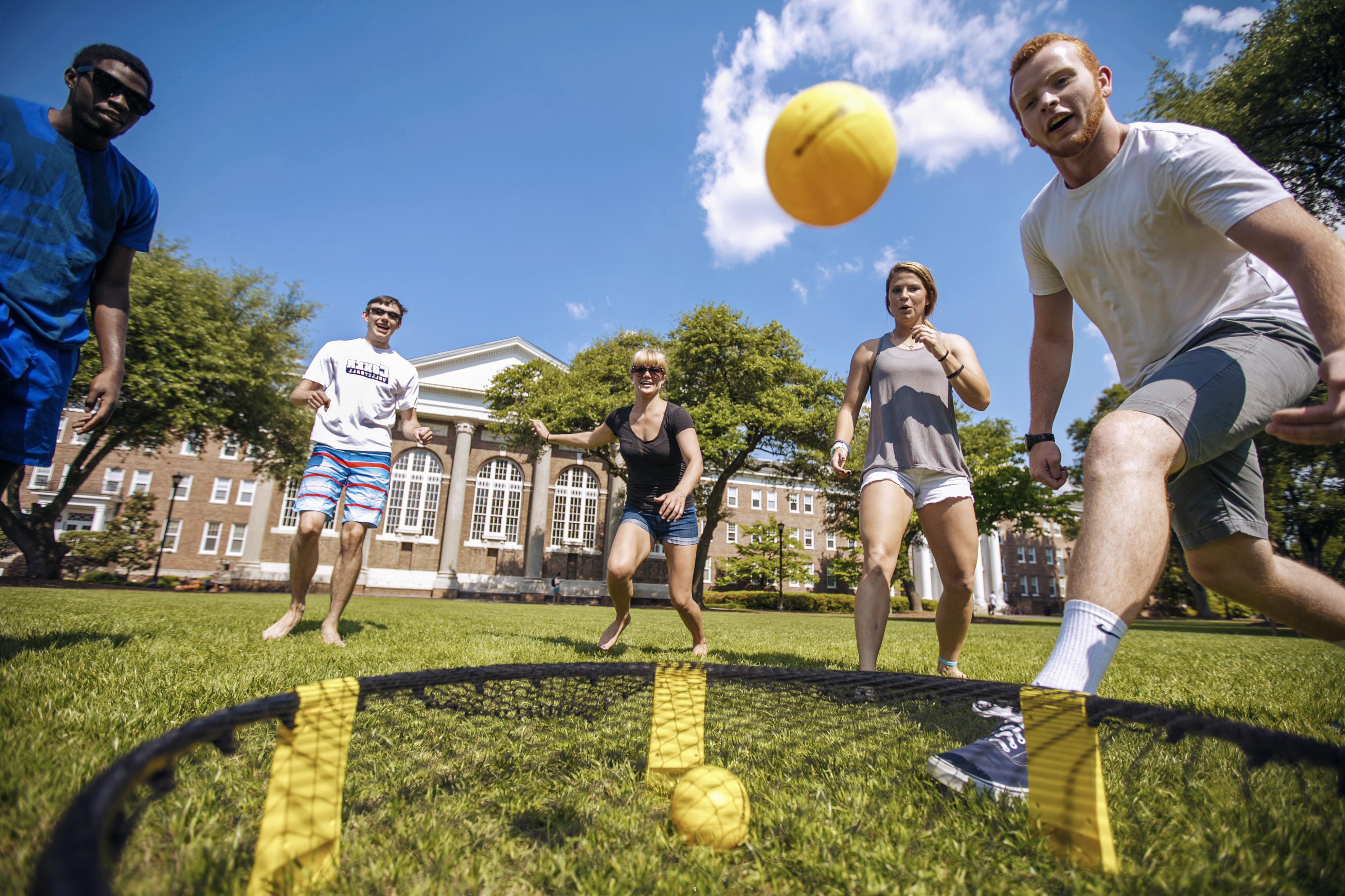 学生 kick a ball around on the Davidson Hall lawn on a sunny afternoon